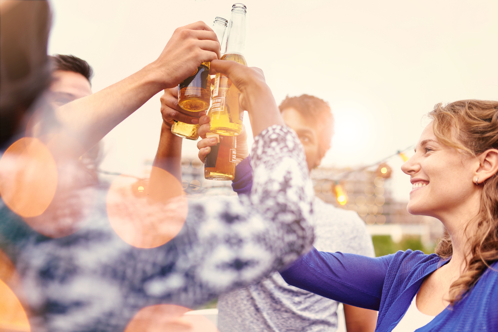 Multi-ethnic millenial group of friends partying and enjoying a beer on rooftop terrasse at sunset-1