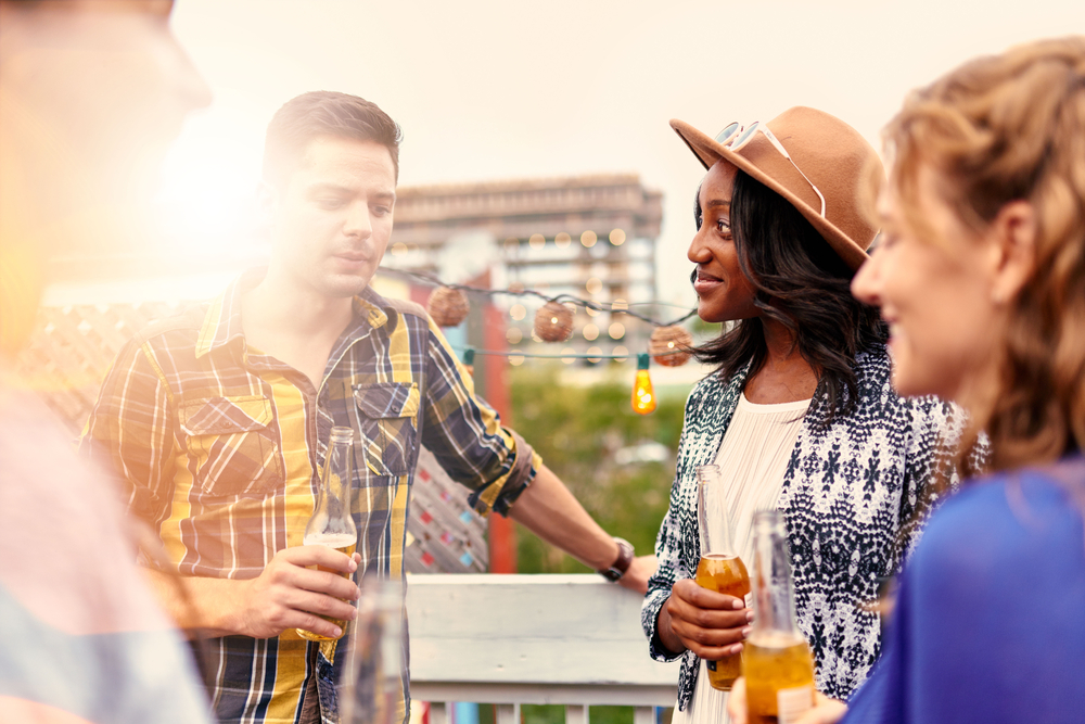 Multi-ethnic millenial group of friends partying and enjoying a beer on rooftop terrasse at sunset-3
